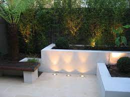 chic little courtyard raised beds and bench with limestone paving bamboo uplit at night small garden design garden design modern garden design
