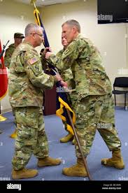 Colonel Jeff Olive, commander of the 122nd Regiment, Regional Training  Institute transfers the regimental colors to incoming Regimental Command  Sgt. Major Patrick Eaton (left) during a change of responsibility at RTI  headquarters