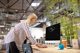 Modern Office. Blonde Woman Bending Over Desk, Looking At Screen. Stock  Photo, Picture and Royalty Free Image. Image 143586228.