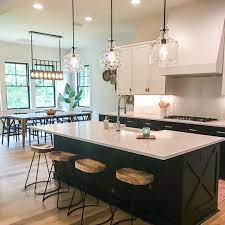 The black and white combination with a tint of wood looks just perfect. Modern Farmhouse With Two Toned Kitchen Cabinets Matte Black Clear Glass Island Pendants Farmhouse Kitchen Lighting Modern Kitchen Modern Farmhouse Kitchens