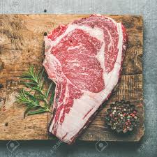 It's an expensive cut of meat but also one that's tender, juicy and filled with flavor. Flat Lay Of Raw Prime Beef Meat Dry Aged Steak Rib Eye With Seasoning On Rustic Wooden Cutting Board Over Grey Concrete Background Top View Copy Space Square Crop Meat High Protein Dinner Concept Stock Photo