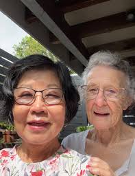 This is Marjorie looking over the shoulder of Ruby, our chief cutter. They  regularly meet at Chapel Hill where Ruby picks up a stack of beautifully  sewn clothes that Marjorie has made