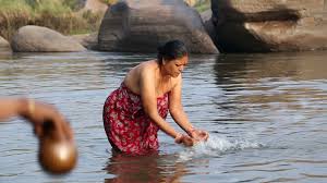 HAMPI, INDIA - 28 JANUARY 2015: Indian woman standing in the river and  taking bath.