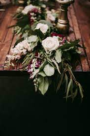 On Varnished Farm Tables Lush Garlands Of Lemon Leaf Seeded Eucalyptus Willow E Wedding Table Garland Wedding Floral Centerpieces Wedding Table Centerpieces