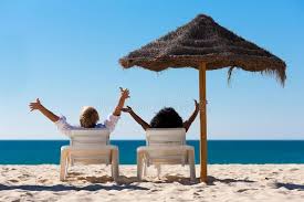 Couple On Beach Vacation With Sunshade Couple Sitting In Sun Chairs Under An Pa Aff Sun Best Places To Retire Summer Vacation Destinations Beach Vacation