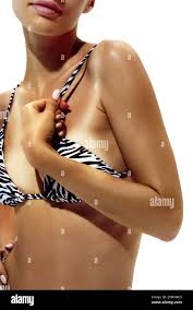 Woman pulls at her zebra-print bikini strap, showing clear tan lines on her  deeply tanned skin against white studio background Stock Photo - Alamy