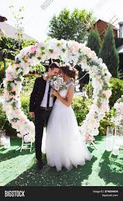 Amazing Wedding Couple Near The Wedding Arch Pretty Bride And Stylish Groom Wedding Couples Wedding Arch Wedding