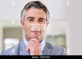 Mature business executive standing next to large windows in a top floor  office looking at the view of the harbour while talking logistics