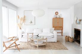 A boho living room with folksy artworks and pillows, leather and velvet ottomans, potted plants and a comfy sofa. How To Create The Perfect Scandi Boho Home Style Te Esse By Velvet