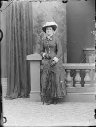Unidentified Woman With Umbrella Wearing Fancy Hat And Dress Which Is Tight Over The Hips Layer Over Pleated Skirt Fancy Hats Pleated Skirt Victorian Costume