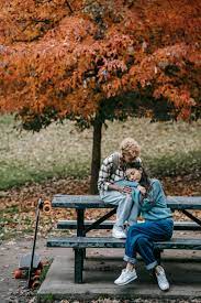 Young lesbian couple sitting with boards and caressing near autumn tree ·  Free Stock Photo