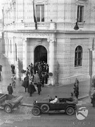 La bcc di napoli, la banca della città. Vittorio Emanuele Accompagnato Da Un Folto Gruppo Di Persone Ripreso Di Spalle Entra Nella Sede Del Banco Di Napoli Di Brindisi Archivio Storico Istituto Luce