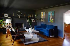 In this living room designed by heidi caillier, the jute rug, wood finishes, and brass accents are reflected by the paint color while the cool marble veins and blue pops contrast with it nicely. 20 Gorgeous Black Living Rooms How To Use Black Walls Decor In Living Rooms Apartment Therapy