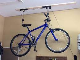 Bicycle hoisted and excess pulley rope attached to wall holder. How To Install A Bicycle Lift On Your Garage Ceiling B C Guides