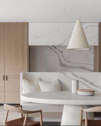 A cozy scandi bedroom with printed wallpaper, a white wooden floor, a white bed and a rough wooden bench at the foot. Kmaeoketkaleem