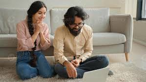 Multiracial couple Arabian man and Indian woman on floor family couple  homeowners wife girlfriend and husband boyfriend watching laptop movie  smart TV enjoy home leisure smiling talk call smile 55178850 Stock Photo