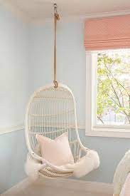These hanging chairs are made for both inside and outside. A White Serena Lily Rattan Hanging Chair Topped With A Faux Fur Throw And A Pale Pink Pill White Hanging Chair Bedroom Hanging Chair Chair Rail Ideas Bedroom