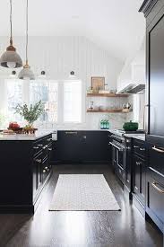A black range hood is fixed to a white shiplap wall between brass and glass faceted pendants and over a stainless steel range placed between light gray cabinets. Redesign Home Llc Kitchen Remodel Small White Kitchen Remodeling Kitchen Design