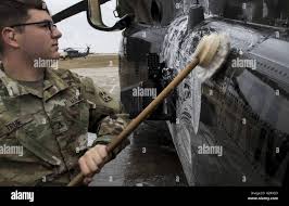 Army Pfc. Gregory True, a UH-60 blackhawk helicopter mechanic with C  Company, 3rd Battalion, 4th Combat Aviation Brigade, cleans the side of a  UH-60 blackhawk Nov. 6, 2018 at Mihail Kogalniceanu Air