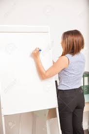 rear view of a young female teacher writing on a flip chart and