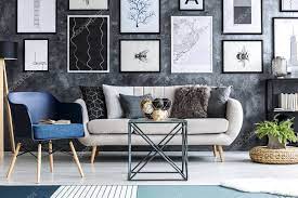 Book and plant on a diamond shape side table, sofa and pink armchair in an elegant, white living room interior with framed posters gallery. Blue Armchair Next To A Beige Sofa In Living Room Interior With Plant On Pouf And Posters On Grey Wall 202813194 Larastock