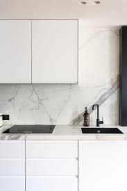 La cuisine avec son plan de travail dekton autour de levier et de la plaque de cuisson et la table en bois de 24m. Cuisine En Marbre Blanc Credence Cuisine Blanche Marbre Cuisine Cuisine Moderne Blanche