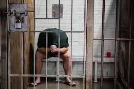 A person in his cellule, in jail, behind the bars