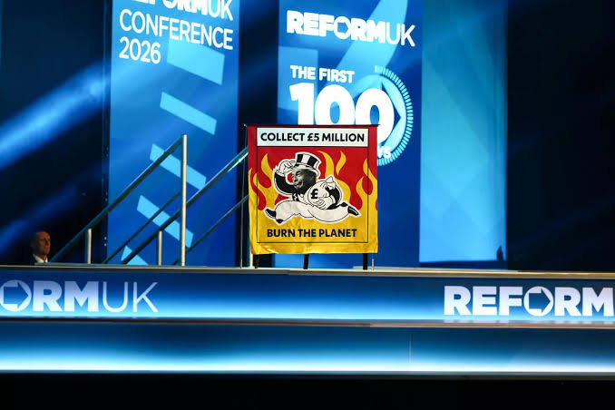 The remote-controlled banner on the Reform UK conference stage., do AI tạo