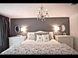 A small modern bedroom with black and white walls, a grey bed, leather stools and lamps and bulbs. Luxury Bedroom Designs For Small Rooms