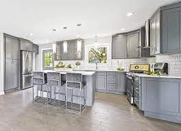 There are lots of contrasting finishes going on in this transitional kitchen—hardwood floors, a natural stone accent wall, dark grey cabinets and a waterfall marble island contribute to the unique rustic design. Types Of Kitchen Floor Tiles Design Guide Designing Idea