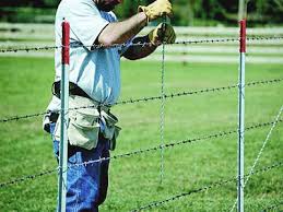 A close up of a section of old rusty barbed wire fencing set against a blue sky with fluffy clouds. Barbed Wire Fence Stay Tightens And Stabilizes Barbed Wire Fence