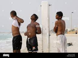 MEN USE THE PUBLIC SHOWERS ON THE JUMEIRAH PUBLIC BEACH BY THE BURJ AL ARAB  HOTEL Stock Photo - Alamy
