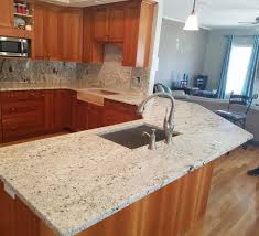 The center kitchen island has a veggie sink on it along with pendant lights above it. Biscotti White Granite Kitchen Countertop Granite Vanity Tops