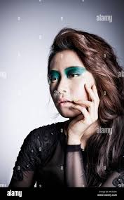 Side view portrait of young Korean woman in black clothes and green eye  shadow touching her face Stock Photo