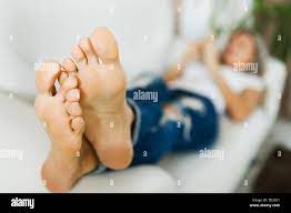 Nackte Füße der Frau in Jeans mit smart phone liegen auf weißen Sofa  Stockfotografie - Alamy