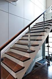 Steel And Wood Stairs With A Glass Handrail Lead Up To The Second Floor Of This Modern House S Glass Railing Stairs Stair Railing Design Modern Stair Railing