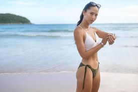 jovem mulher bonita de biquíni relaxando e usando smartwatch na praia,  verão, férias, feriados e conceito de saúde. 9284487 Foto de stock no  Vecteezy