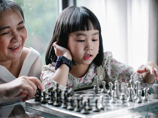 Parent and child practising beginner chess opening moves together at home