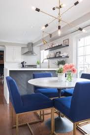 A Modular Chandelier Hangs Over A Round Marble Top Dining Table Surrounded By Cobalt Blue Di Blue Dining Chair Transitional Dining Room Marble Top Dining Table