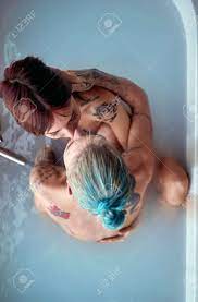 A Young Sexy Tattooed Lesbian Couple In A Hug Kissing While Enjoying A Bath  In A Relaxed Atmosphere In The Bathroom With A Money In The Water. Love,  Relationship, Luxury, Bath, Lgbt