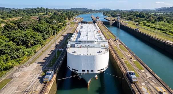 A large cargo ship navigating through the narrow Panama Canal locks.