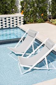 White And Gray Pool Loungers Sit On A Tanning Ledge In An In Ground Swimming Pool Accented With Peacock Blue Line Pool Lounger Tanning Ledge Pool Modern Pools