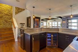 This basement kitchen has stone wall design and white cabinets on top of the sink. Costs And Considerations Of Building A Basement Kitchen Hgtv