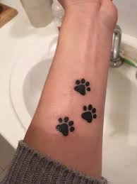 The model next to the finished product. 25 Paw Print Tattoo Kleiner Handgelenk Unterarm Katze Tatowierung Forearm Tattoos Pawprint Tattoo Small Forearm Tattoos