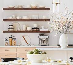 White and gray contemporary kitchen boasts wood floating shelves mounted to gray grid backsplash tiles on either side of a stainless steel hood fixed above a stainless steel oven range. Brighton Floating Wood Shelves Pottery Barn