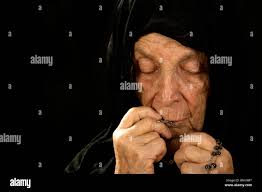 Catholic Old Woman Deep in Prayer wearing a black Veil Stock Photo
