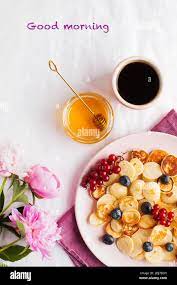 Pequenas Panqueques Con Bayas Miel Flores Cafe Y Las Palabras Buenos Dias Concepto De Desayuno Fotografia De Stock Alamy