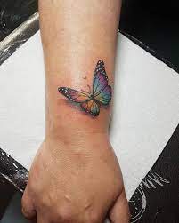 Image May Contain One Or More People And Closeup Butterfly Wrist Tattoo Butterfly Tattoo Colorful Butterfly Tattoo