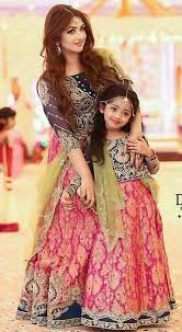 Fascinating curly mother and beautiful trendy daughter in the same outfit posing together after birthday party. Pakistani Actress Mother And Daughter Same Dress Design Mother Daughter Latest Dress Collocation Kids Dress Mother Daughter Dress Mom Daughter Outfits