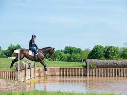 Horse cross country teenage competition jumping tree trunks and jumps over barrels of water and colored bars. Cross Country Confidence With Tina Cook Horse And Rider